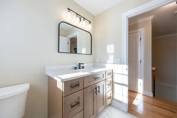 a bathroom with a toilet sink vanity and mirror