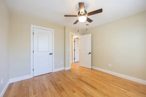 an empty room with wooden floor and ceiling fan