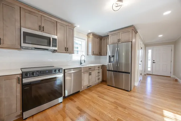 a kitchen with a stove a microwave oven a refrigerator a sink and dishwasher with wooden floor