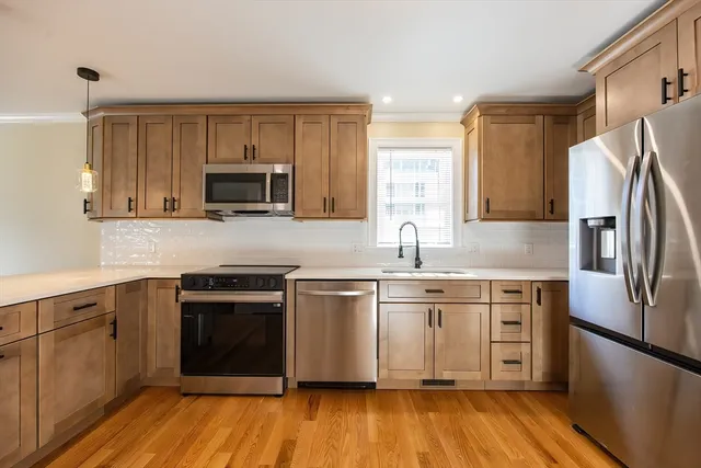 a kitchen with stainless steel appliances granite countertop a stove top oven a sink and dishwasher a refrigerator with wooden floor