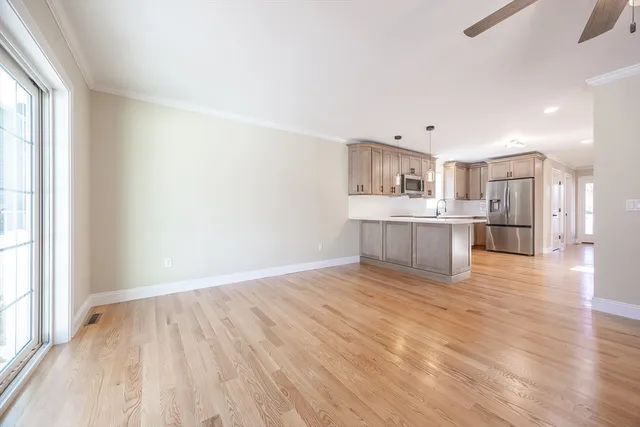 an empty room with wooden floor chandelier fan and windows