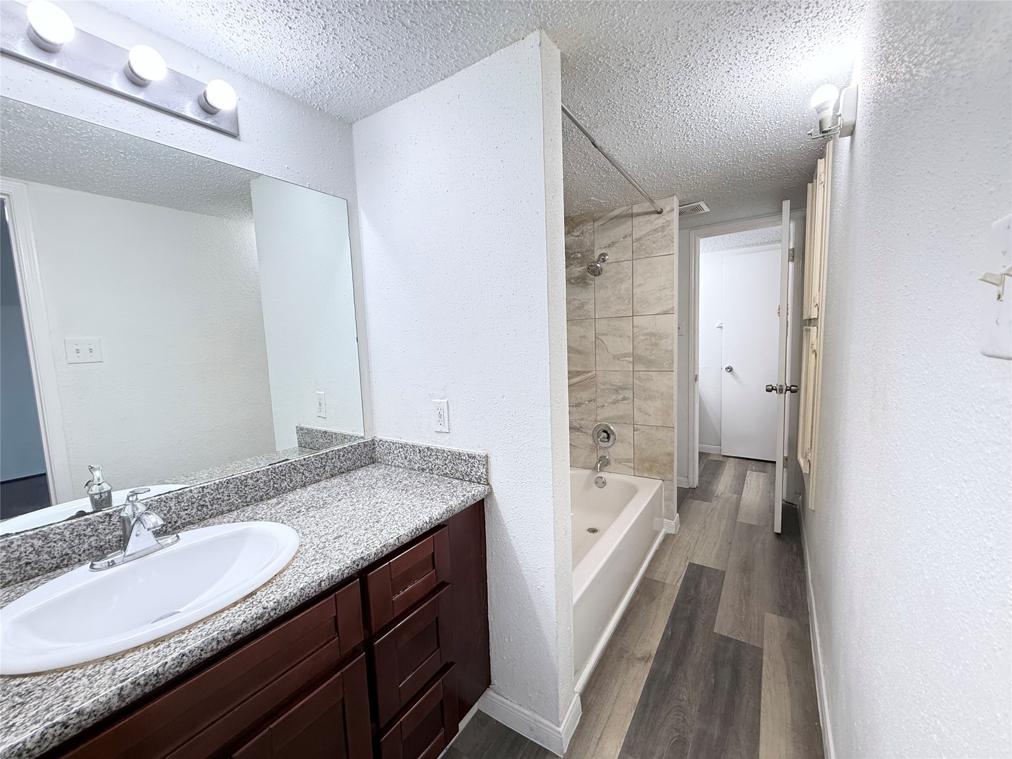 7789 Cook Road Houston, TX 77072 - Photo 16 of 18 a bathroom with a granite countertop sink a mirror and a bathtub