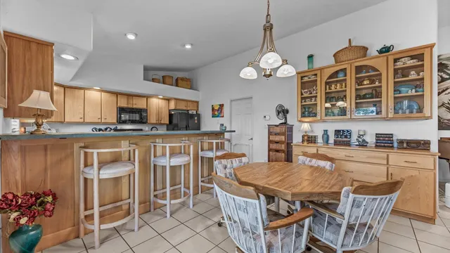 a kitchen with stainless steel appliances granite countertop a stove top oven a sink a dining table and chairs with wooden floor