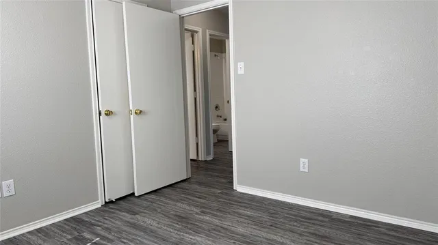a view of an empty room with wooden floor and closet