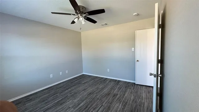 a view of a room with wooden floor and a ceiling fan