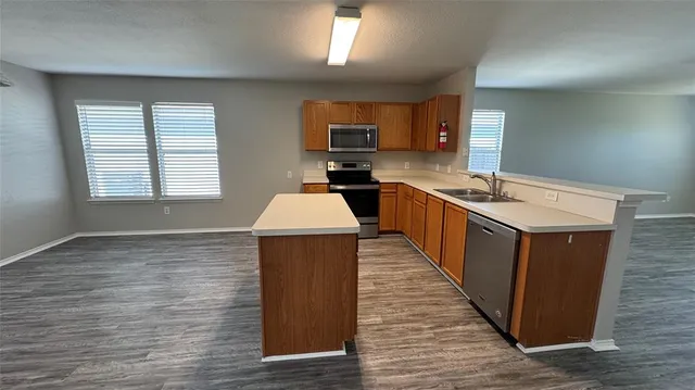 a kitchen with wooden cabinets a sink dishwasher and a stove with wooden floor