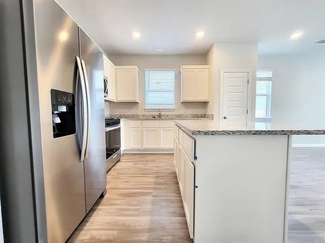 a large kitchen with stainless steel appliances granite countertop a refrigerator and a sink