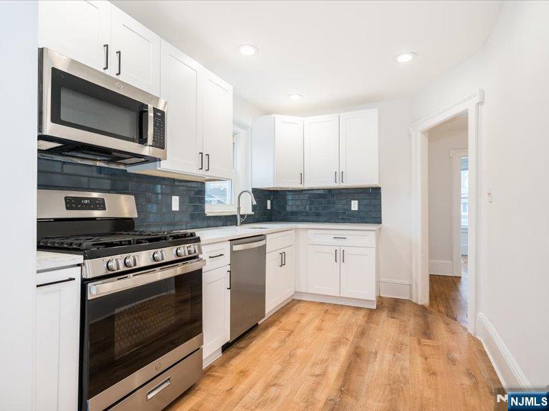 14 Ravine Avenue, Unit 2 Caldwell, NJ 07006 - Photo 6 of 23 a kitchen with stainless steel appliances granite countertop a stove a microwave and cabinets