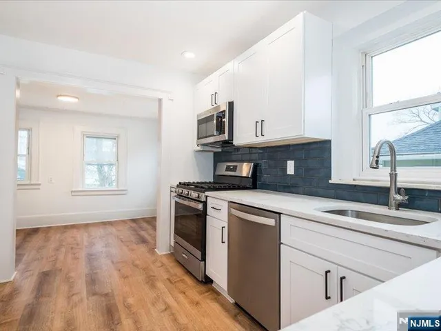 a kitchen with granite countertop a stove a sink and a microwave