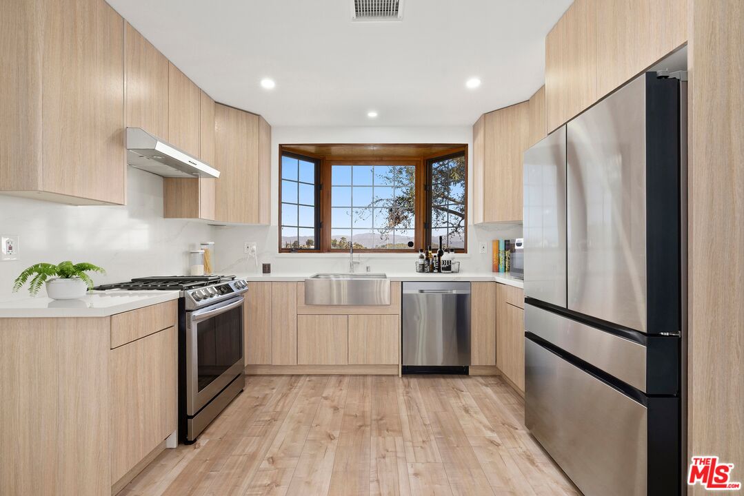 2204 Ridgemont Drive Los Angeles, CA 90046 - Photo 6 of 13 a kitchen with white cabinets stainless steel appliances and window