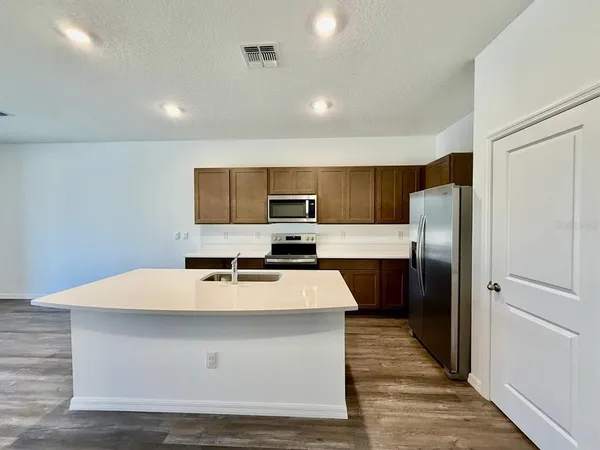 a large kitchen with kitchen island a counter top space a sink and refrigerator