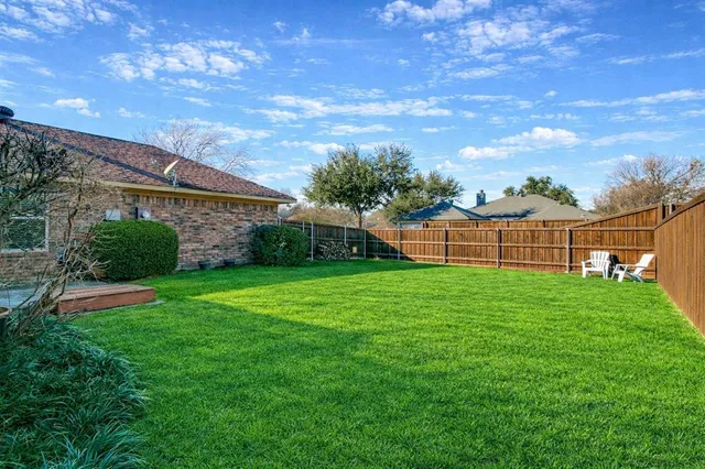a view of a backyard with brick wall and plants