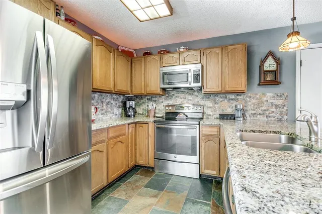 a kitchen with stainless steel appliances granite countertop a refrigerator a stove and a sink