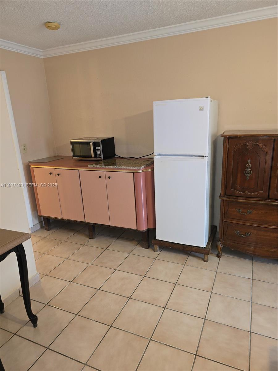 1113 Northeast 2nd Street, Unit 12 Hallandale Beach, FL 33009 - Photo 4 of 6 a kitchen with a refrigerator and cabinets