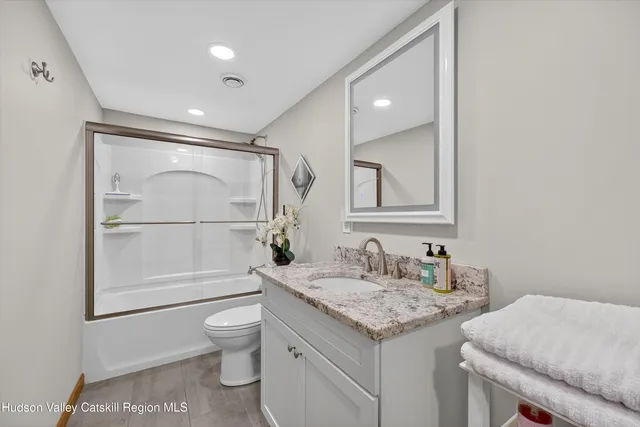 a bathroom with a granite countertop sink toilet a mirror and shower