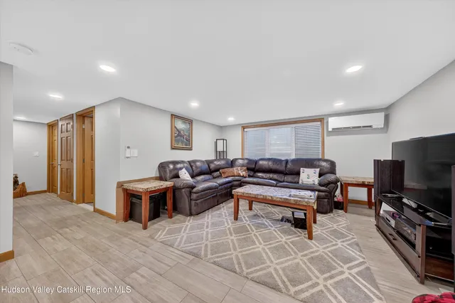 a living room with furniture a flat screen tv and a refrigerator