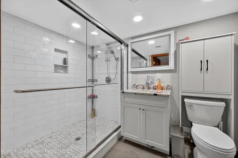 a bathroom with a shower sink vanity mirror and toilet