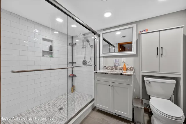 a bathroom with a shower sink vanity mirror and toilet