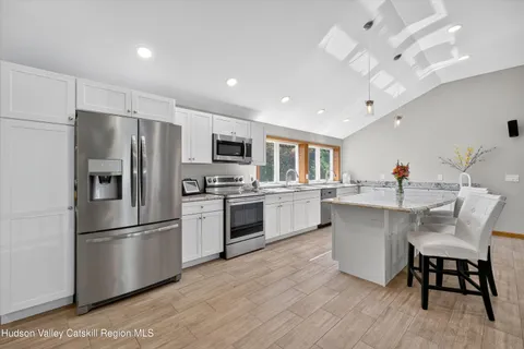 a kitchen with white cabinets stainless steel appliances and dining table