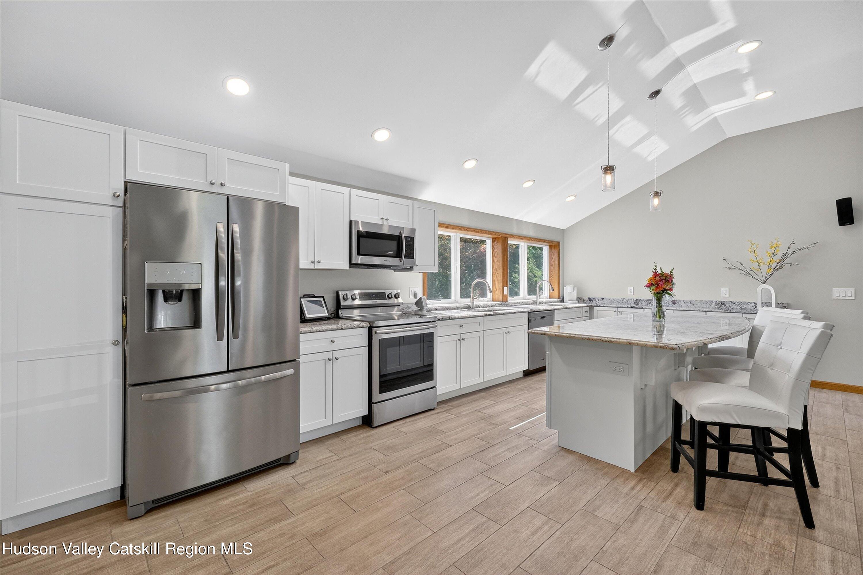 6 Hasbrouck Place New Paltz, NY 12561 - Photo 7 of 38 a kitchen with white cabinets stainless steel appliances and dining table