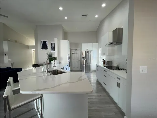 a large white kitchen with kitchen island a sink and a stove top oven