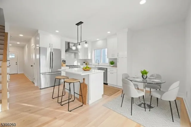 a kitchen with stainless steel appliances kitchen island granite countertop a dining table chairs and white cabinets