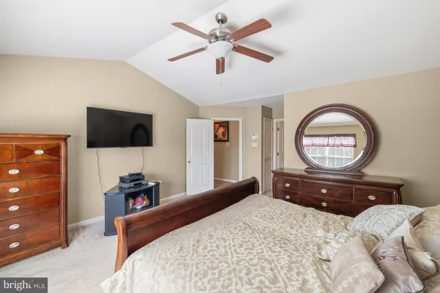a bedroom with a bed a mirror and a flat tv screen on dresser