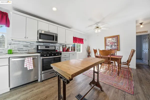 a kitchen with stainless steel appliances granite countertop a stove top oven a sink a dining table and chairs with wooden floor