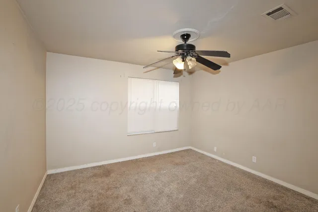 an empty room with a window and a fan
