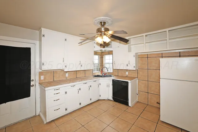 a kitchen with granite countertop a refrigerator and a stove top oven