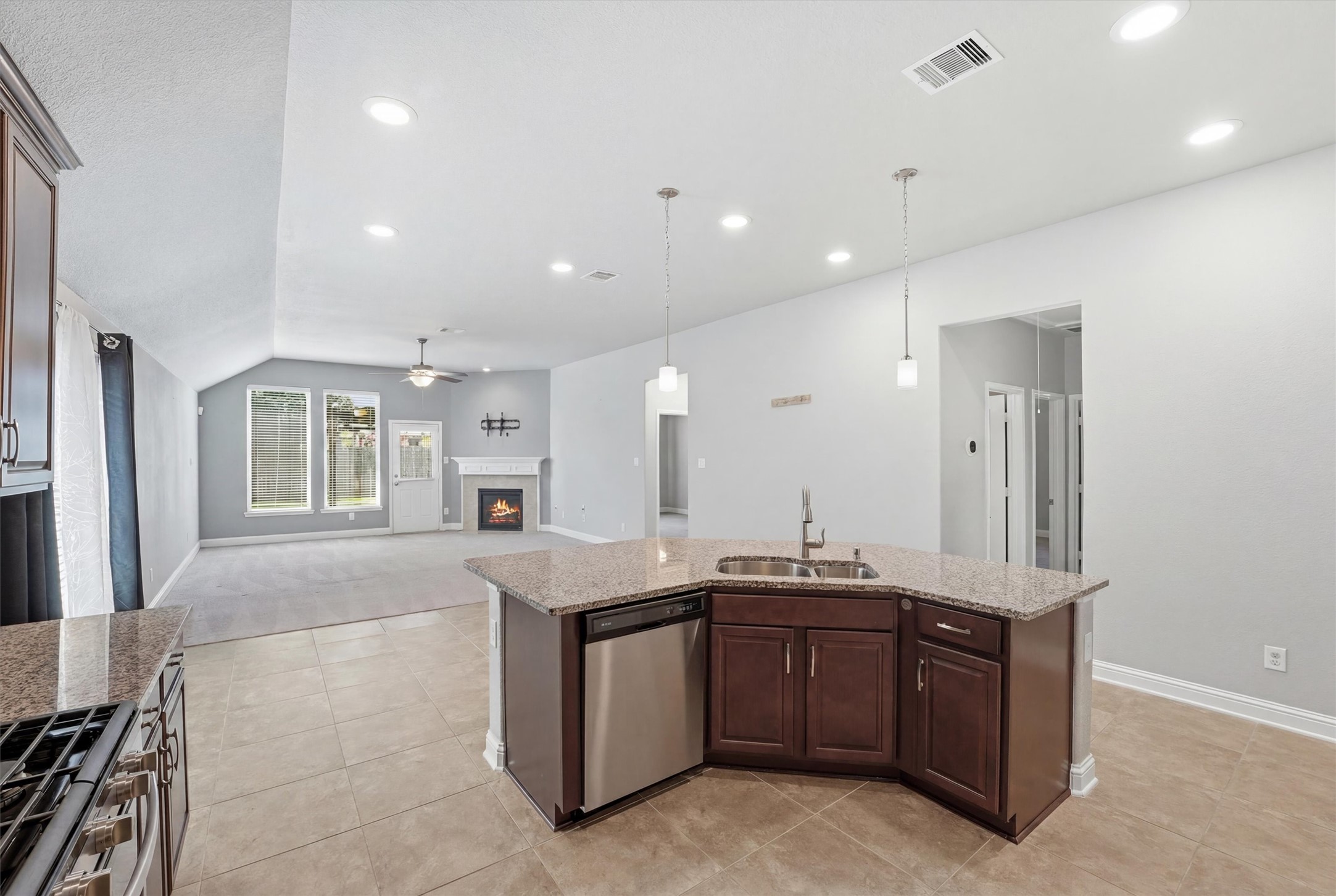 1911 Cedar Ridge Lane Pearland, TX 77089 - Photo 10 of 33 Island kitchen with granite counters, tile backsplash, 42 inch cabinets, and stainless steel appliances - *fireplace virtually lit*