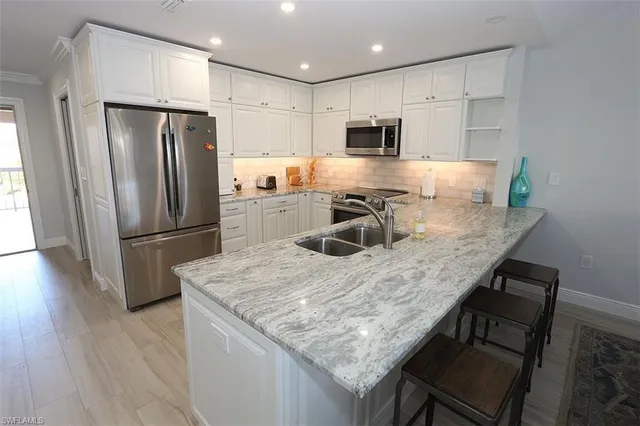 a kitchen with stainless steel appliances granite countertop a table chairs refrigerator and microwave