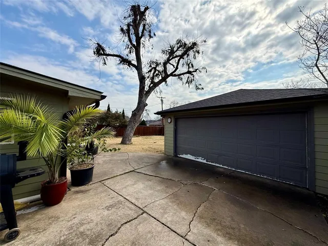 a backyard of a house with potted plants and large tree