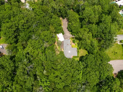 an aerial view of residential house with outdoor space and trees all around