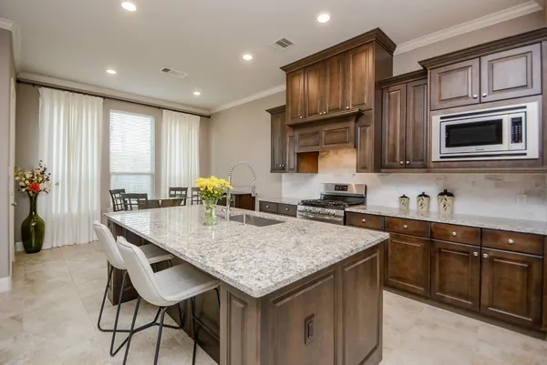 a kitchen with granite countertop kitchen island stainless steel appliances a stove sink microwave and cabinets
