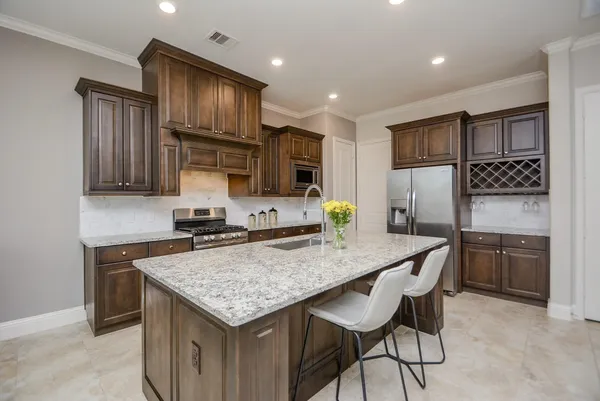 a kitchen with granite countertop a table chairs stainless steel appliances and cabinets