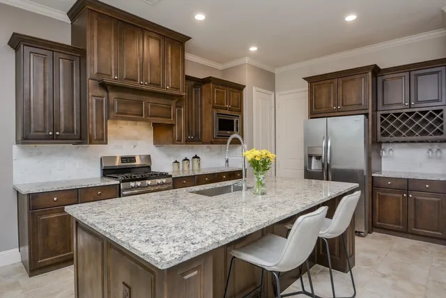 a kitchen with granite countertop kitchen island stainless steel appliances and wooden cabinets