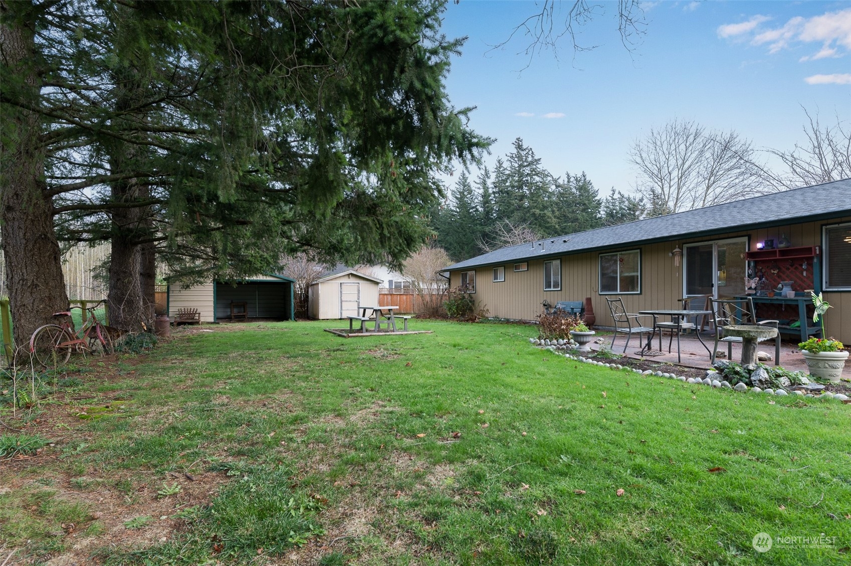 730 East Del Ray Road Lynden, WA 98264 - Photo 31 of 40 a view of a backyard with table and chairs potted plants and large tree