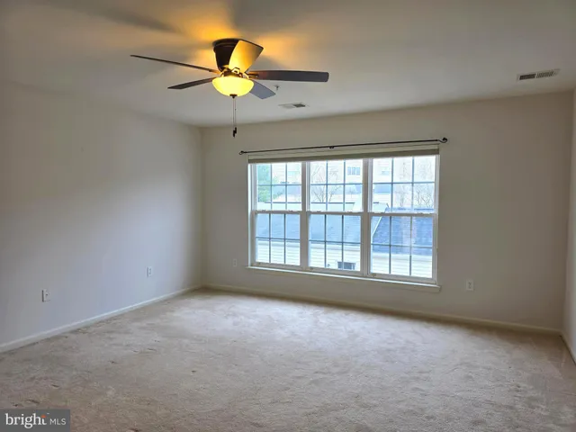 an empty room with a window and a fan