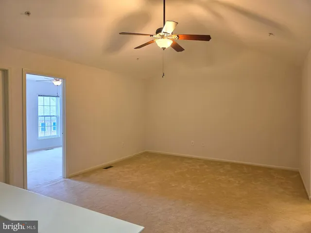an empty room with a ceiling fan and carpet
