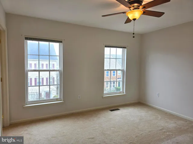 an empty room with windows and fan