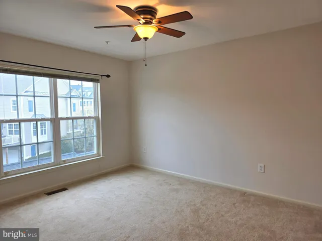 an empty room with windows and fan