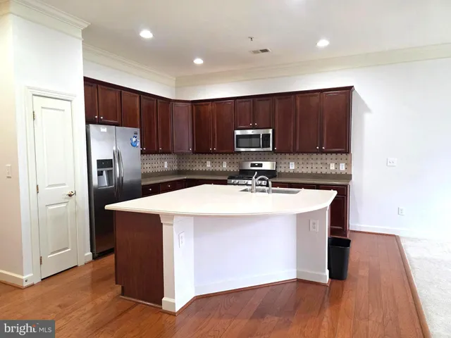 a kitchen with kitchen island a sink refrigerator and cabinets
