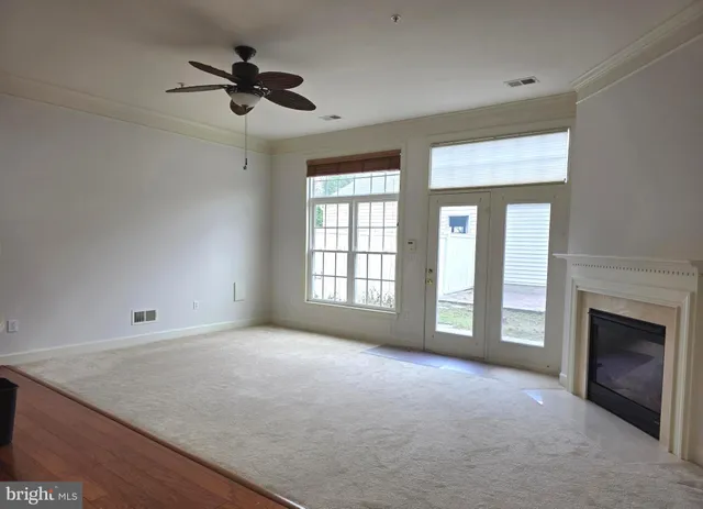 an empty room with chandelier fan and windows