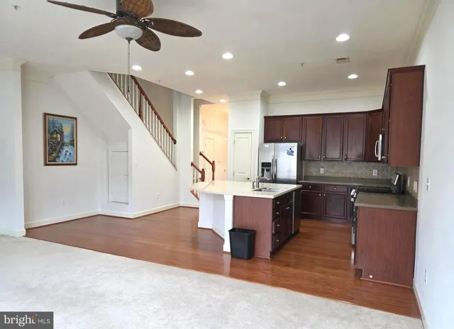 a kitchen with kitchen island stainless steel appliances sink cabinets and wooden floor