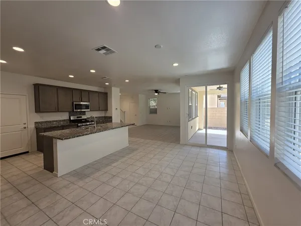 a large kitchen with stainless steel appliances kitchen island granite countertop a refrigerator a sink and a stove