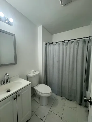 a bathroom with a sink a toilet a mirror and shower curtain