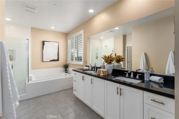 a bathroom with double vanity sinks a large mirror and a bathtub