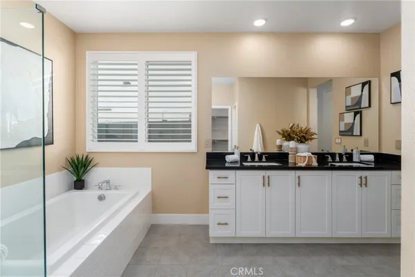 a bathroom with a granite countertop bathtub a sink and a large mirror