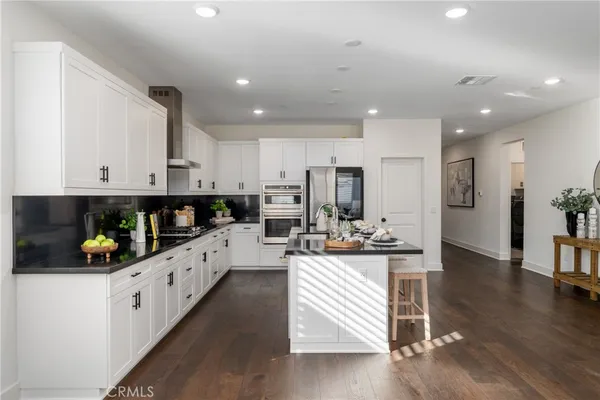 a kitchen with stainless steel appliances kitchen island granite countertop a refrigerator and a stove top oven